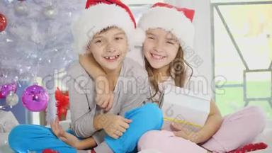有趣的视频，<strong>兄妹</strong>戴着圣诞帽，温柔地拥抱，分享圣诞礼物，坐在白色的帽子上